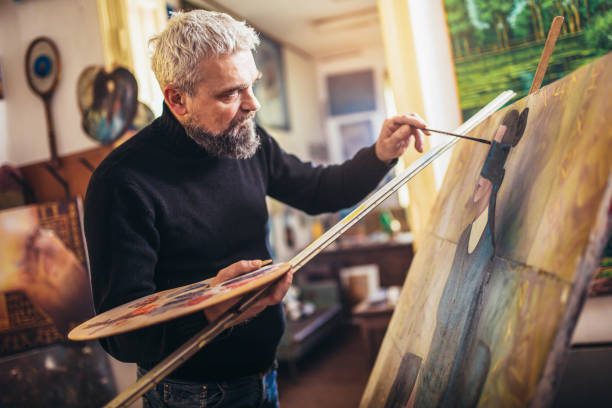 istock Mature man painting on canvas in art studio. 1207463611