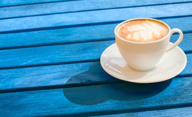 istock hot latte coffee with latte art palm leaf shape in a vintage white coffee cup on a classic blue color wooden table background texture for morning break energy and summer drink concept with copy space 1207465719