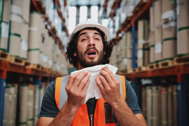 istock Young caucasian warehouse supervisor sneezing while feeling sick of cold 1207465804