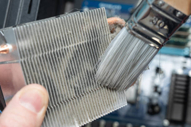 istock Dusty CPU cooler in hand on the motherboard background 1207468942