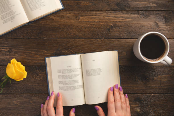 istock Female hands and opened book, on wooden background. Flat lay, top view, copy space. 1207470230