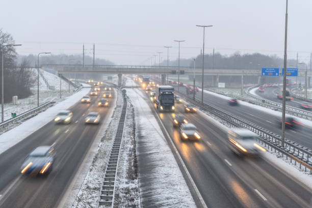 bewegender verkehr auf einer autobahn während eines schneesturms im winter - winterdienst stock-fotos und bilder