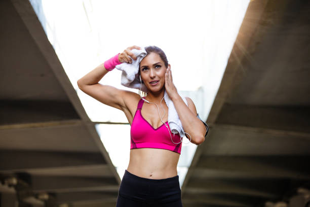 istock Young smiling female resting after an active fitness training while standing against gray wall with copy space area for your text message, satisfied fit woman resting after an active fitness training 1207470929