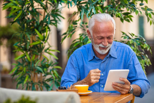 istock Senior man websurfing on tablet in cafe. 1207472317