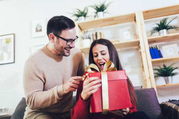 istock Handsome man is giving his girlfriend a gift box 1207473221