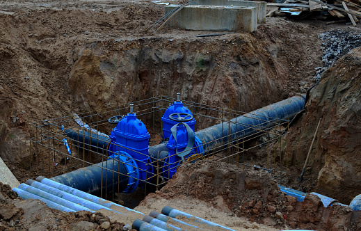 Laying underground storm sewers at construction site, water main, sanitary sewer, drain systems. Groundwater system for new residential buildings in the city. Ball valve background. Small sharpness