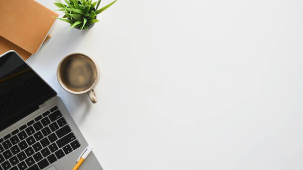 istock Top view image of white working desk with accessories putting on it. Flat lay Computer laptop, Coffee cup, Potted plant, Notebook. Modern and Orderly style workplace concept. 1207479209