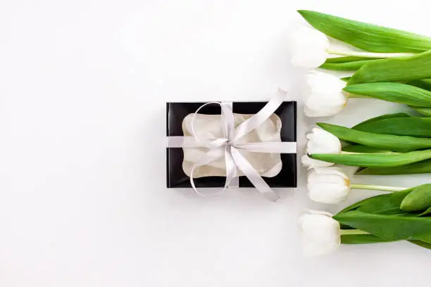 Spring website header template. White tulip black gift box with silver ribbon on light background flat lay. Text place 8 March Happy Mothers Day Sales.Bouquet greeting card. Copy space banner top view