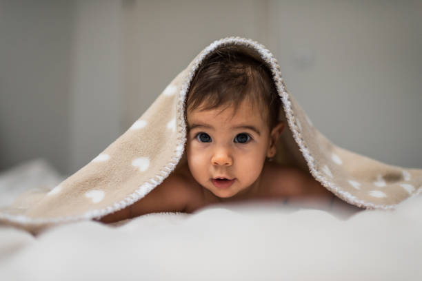 istock Cute baby girl in bed under a fluffy blanket 1207483984