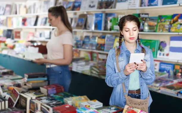 Girl chatting on screen tablet and shopping literature books