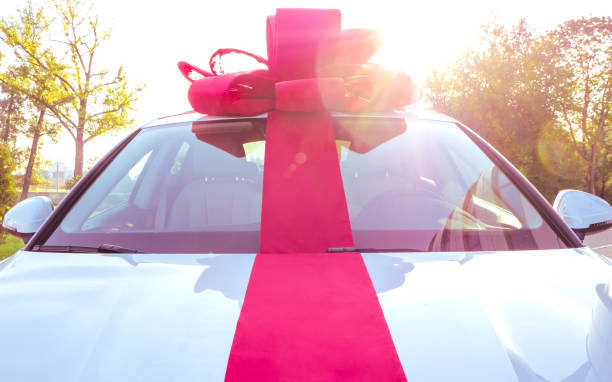 istock New car gift. New white car with red gift ribbon. 1207485068