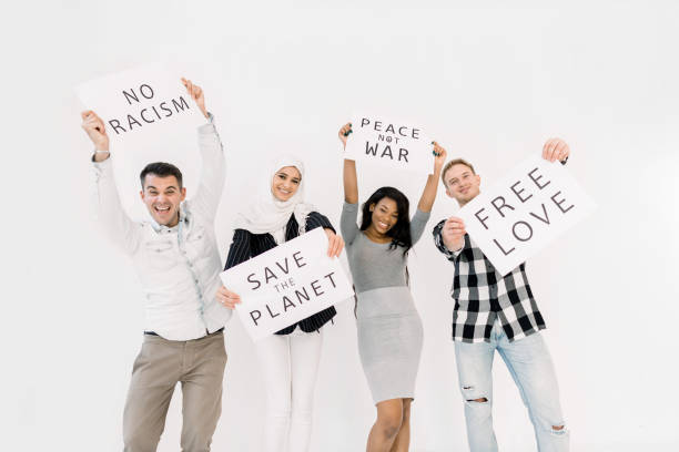 istock Young four multiethnical activists, volunteers, ecologists with banners shouting about racism, saving earth, no war, equal rights, standing isolated on white background 1207487267