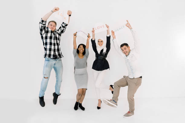 istock Multicultural group of people standing together over white background and holding up different positive slogans on paper sheets. Peace, love, no war, international friendship concept 1207487387