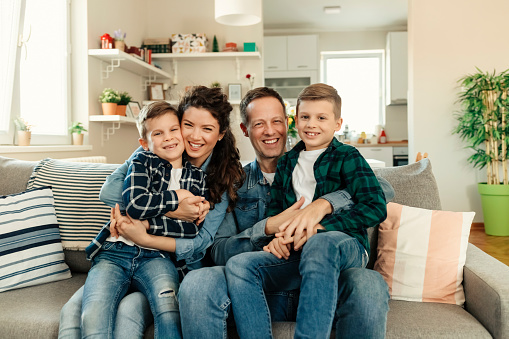 Portrait of a Young Happy Family Smiling at Home Together on the Sofa in the Living Room Enjoy Free Time. Weekend Activity Happy Family Lifestyle Concept