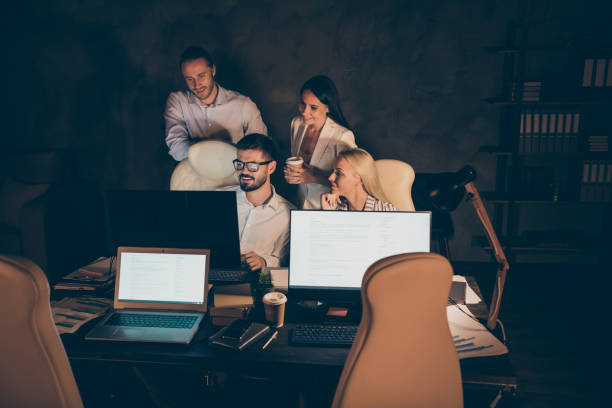 istock Nice attractive cheerful skilled experienced hardworking coworkers partners leaders experts specialists creating new launch startup at night at work place station dark room indoors 1207488512