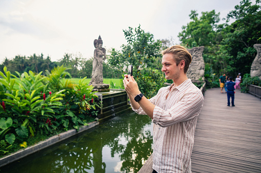 A young man takes time to admire the view in Ubud in Bali and takes a picture.
