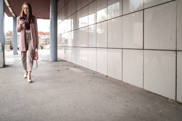 istock Elegant woman walking and text messaging using smart phone after work 1207494245