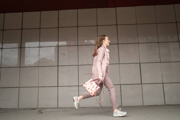 jeune femme élégant dans une ruée à la ville - pink buildings photos et images de collection