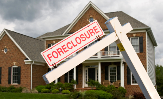 Leaning foreclosure sign in front of a modern single family home on a cloudy cold day