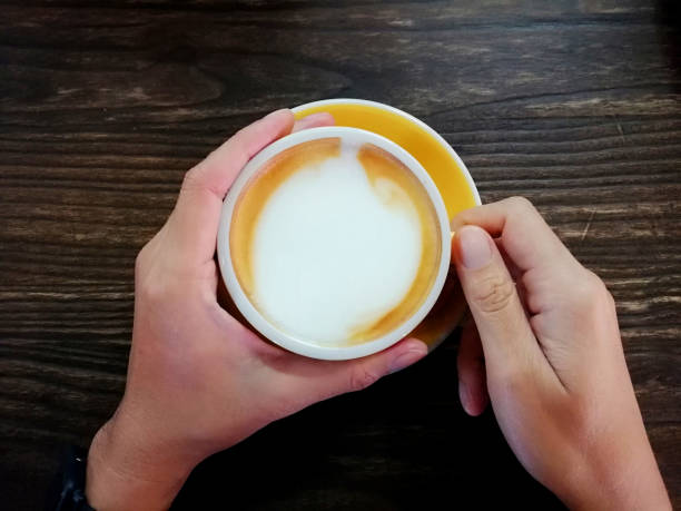 istock Two hand holding a Capucino coffee drinks yellow cup on wooden table backgrounds above 1207495126