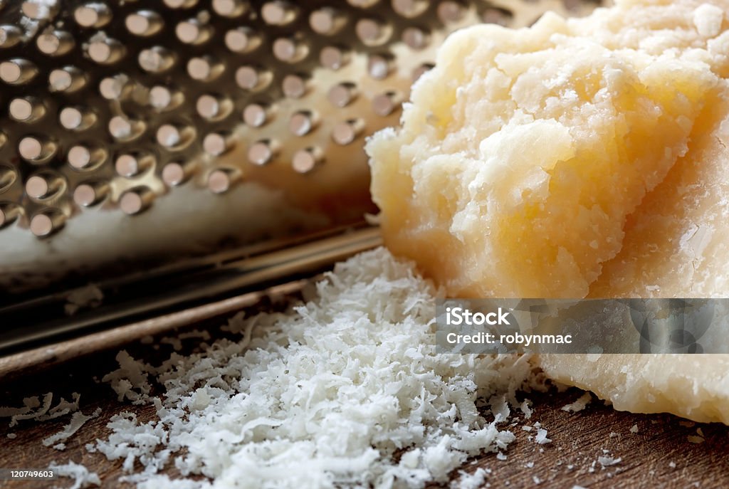 Grated Parmesan Cheese Parmesan cheese with grater.  Shallow depth of field. Cheese Stock Photo