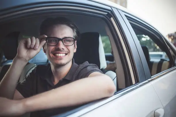 Photo of Close up side portrait of happy caucasian man driving car.