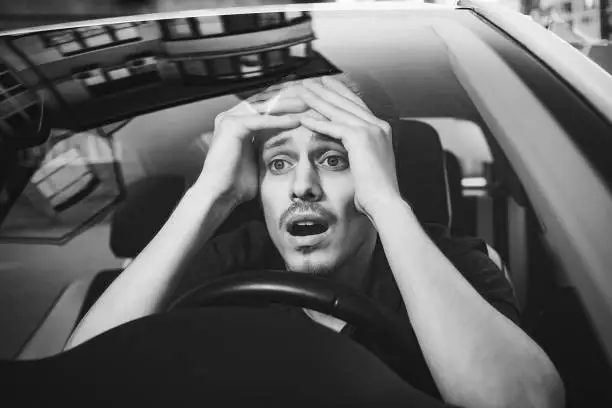 Photo of Young man driving a car shocked about to have traffic accident, windshield view.