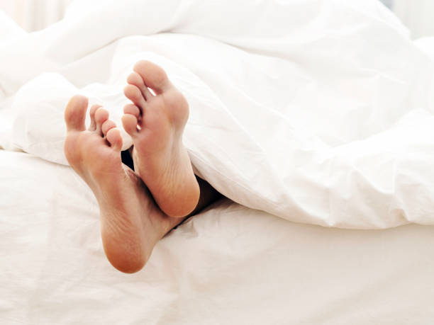uomo pigro e i suoi piedi, sdraiati sul retro su un comodo letto - exhaustion tired men after work foto e immagini stock