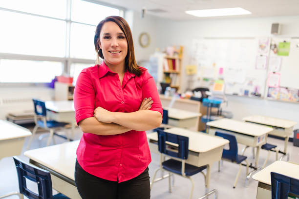 istock Pretty teacher smiling at camera at back of classroom at the elementary school 1207499820