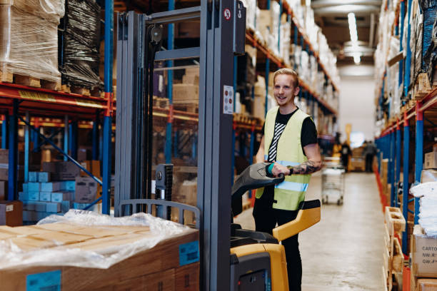 istock Warehouse employee in reflective uniform driving forklif 1207502464