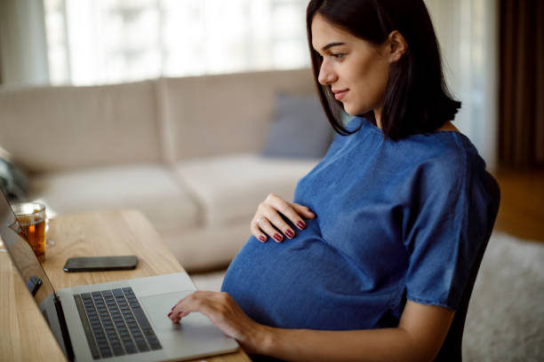 istock Pregnant woman using laptop at home 1207504784