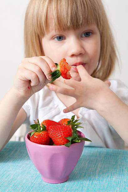 istock LIttle girl eating strawberries 120750853