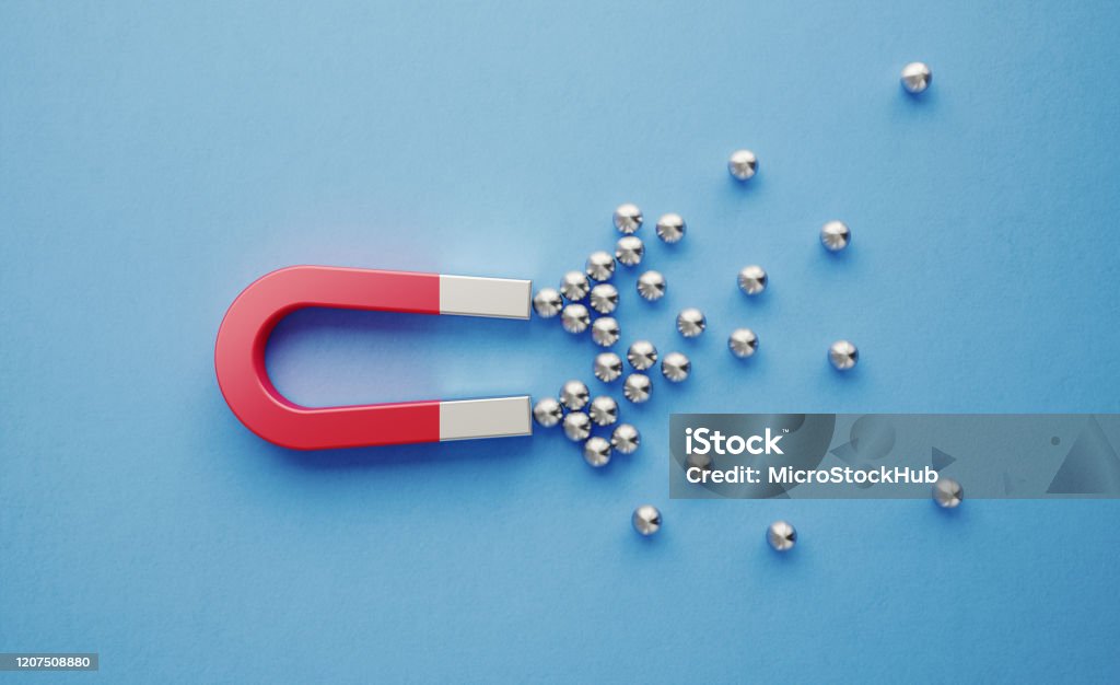 Silver Spheres Gravitated Towards a Red Magnet on Blue Background Silver spheres gravitated towards a red magnet on blue background. Horizontal composition with copy space. Digital marketing concept. Magnet Stock Photo