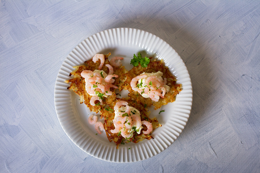 Potato cakes with topping: cream cheese and shrimps on white plate. Vegetable fritters, pancakes. Overhead horizontal image