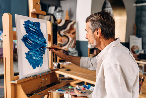 istock Enthusiastic artist working in his studio drawing on canvas 1207511897