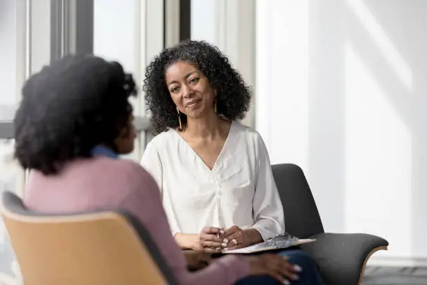 Photo of Mature counselor listens compassionately to unrecognizable female client
