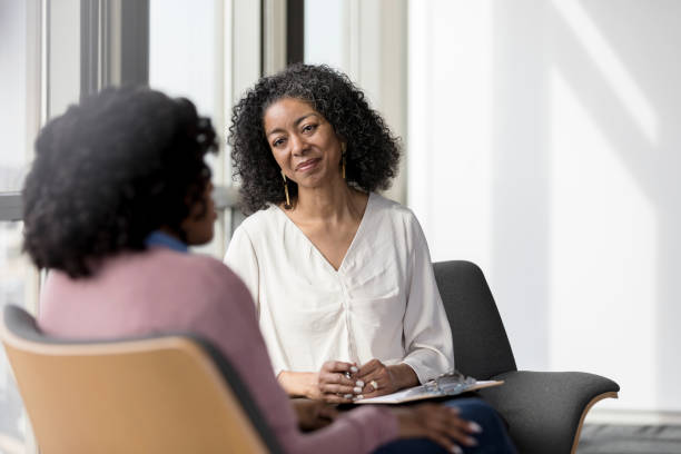 mature counselor listens compassionately to unrecognizable female client - business person listening discussion communication imagens e fotografias de stock
