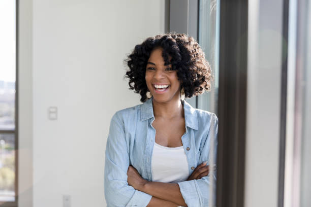 While leaning on the plate glass window, the attractive adult student laughs for a photo.