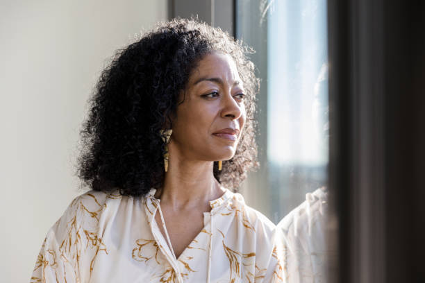 istock Mature adult woman thinks about life while looking out window 1207514129