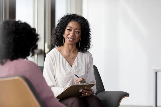istock Female counselor asks questions and documents responses on clipboard 1207514150
