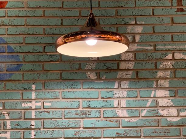 Large black lamp on a background of a white brick wall. A light bulb illuminates a white brick wall. Kiev, the wall in the cafe, February 19, 2020