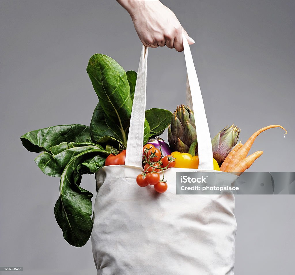 Cotton shopping bag overflowing with vegetables full of vegatables cotton shopping bag carried by a human hand Bag Stock Photo