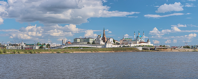 Panorama of Kazan Kremlin, Russia. The image shows in the Kremlin: Governor's Palace or Presidential Palace, Palace Church or Church of Presentation of the Blessed Virgin Mary, cupola of Annunciation Cathedral, Soyembika leaning tower, Taynitskaya tower of fortress wall, northern housing of the Artillery Court, Qol Sharif Mosque, South-west round tower of fortress wall; left of the Kremlin: Palace of Farmers (the building of Ministry of Agriculture). View from the shore of Kazanka river.