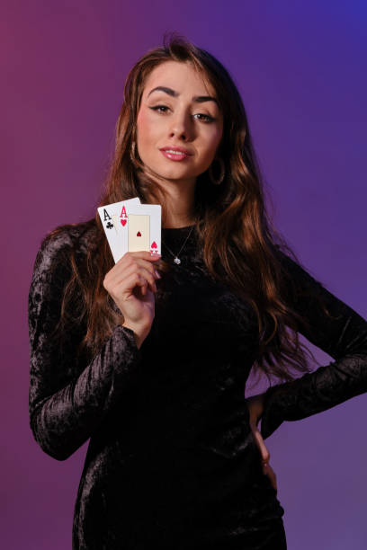 brünette frau in schwarzem samtkleid zeigt zwei spielkarten, posiert vor coloful hintergrund. glücksspiel unterhaltung, poker, casino. nahaufnahme - jewelry glamour brown hair stage makeup stock-fotos und bilder