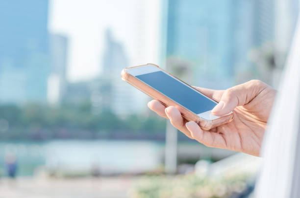 istock close up business man using hand typing smartphones and touch screen working search with app devices outdoor in city with sunrise and building background. 5G technology world wide web connecting. 1207528172