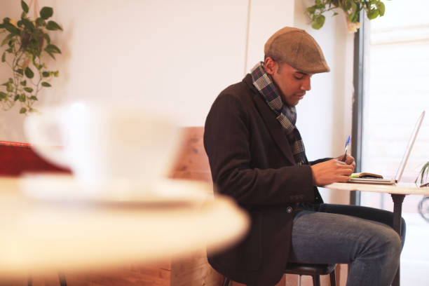 istock One young Afro-American hipster man writing down notes in a coffee shop. 1207528511
