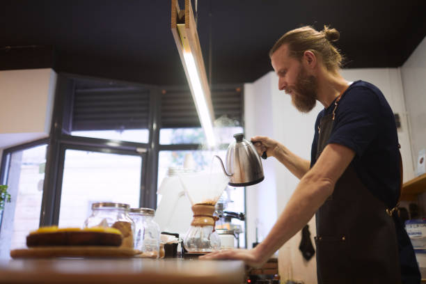 istock One hipster barista preparing pouring water for filtered coffee. 1207528542
