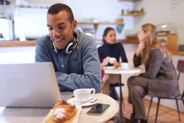 istock Young male freelancer working in a coffee shop with a laptop. 1207529639