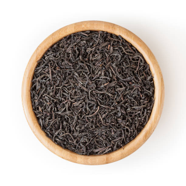 istock Dried black tea in wooden bowl isolated on white background with clipping path 1207531428