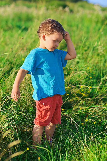 istock Little boy thinking hard standing on green grass lawn 120753162